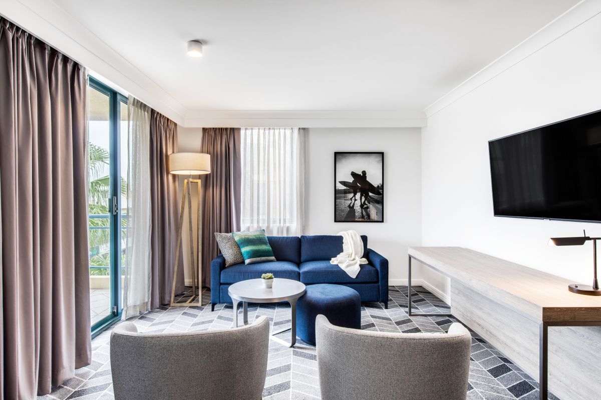 The lounge room in this two-bedroom apartment features a grey and navy colour palette.